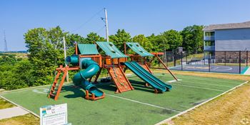 a playground with a swing set and slides on a tennis court